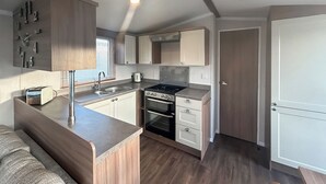 Una cocina compacta con estufa, horno y pileta integrados, alacenas de madera y encimera.