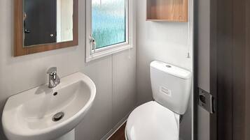 A bathroom with a white sink, toilet, and a window with a view of trees.