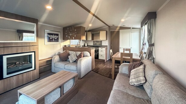 Un espacio habitable compacto con sofá, una pequeña mesa, televisión y kitchenette.