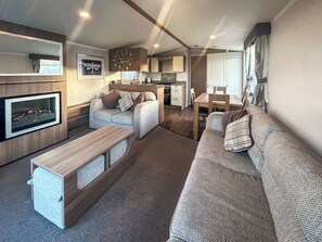 Un espacio habitable compacto con sofá, una pequeña mesa, televisión y kitchenette.