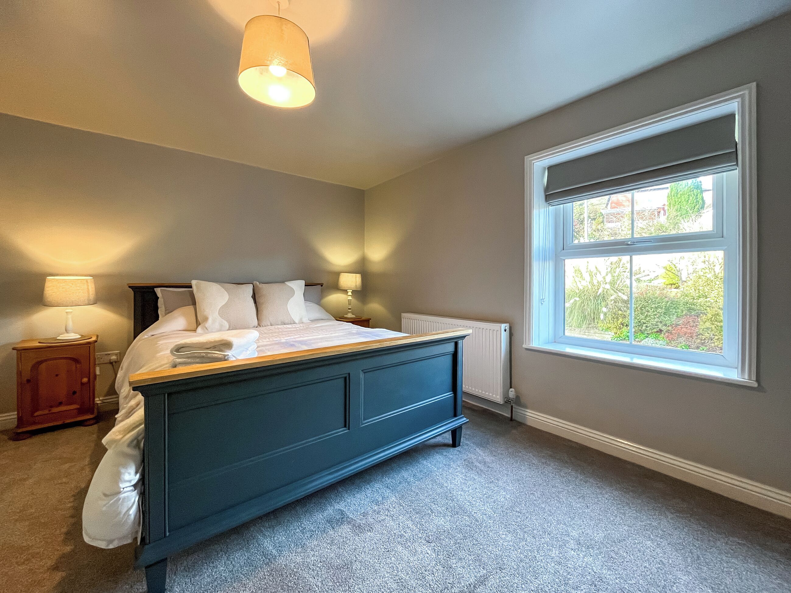 Une chambre à coucher avec un lit, des lampes de chevet, une fenêtre et un radiateur.