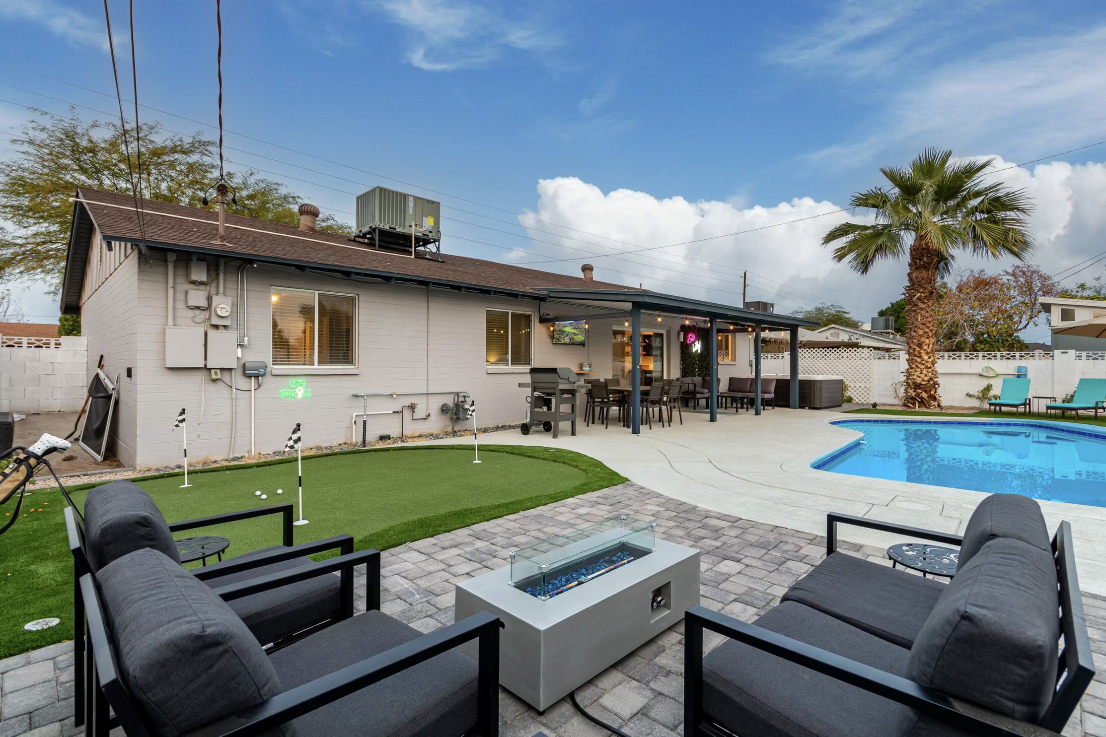 A backyard with a pool, outdoor seating, and a house.