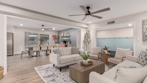 A spacious living room with a modern design, featuring a large sofa, a coffee table, and a dining area with a table and chairs. - Old Town Dream- Pool, Hot Tub, Firepit, Foosball, Cornhole, and Mini Golf (Scottsdale)