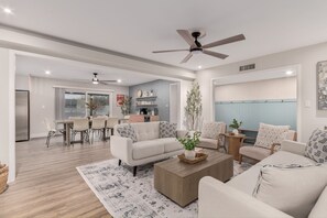 Ein geräumiges Wohnzimmer mit modernem Design, das ein großes Sofa, einen Couchtisch und einen Essbereich mit Tisch und Stühlen bietet.
