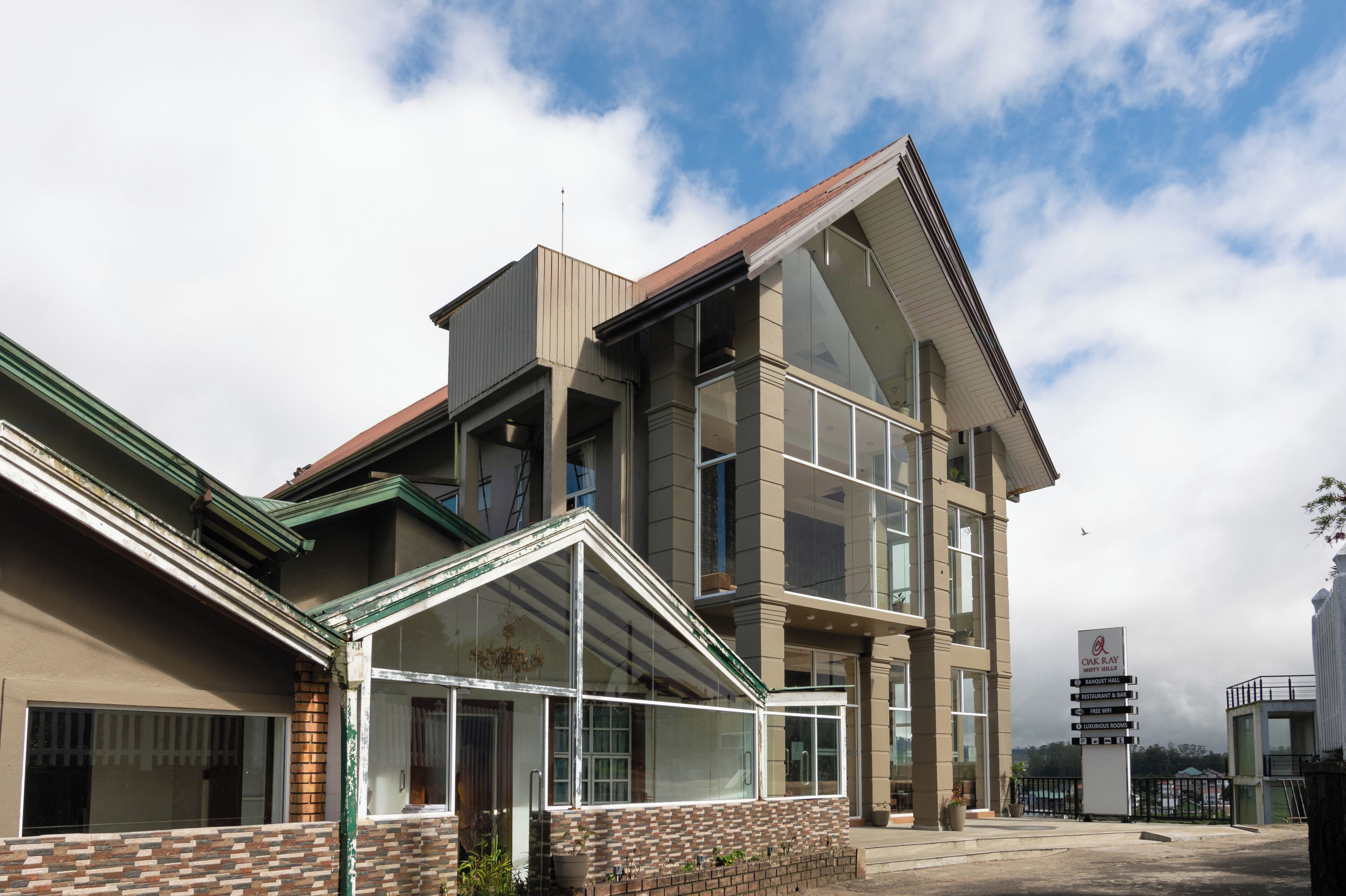 A modern building with a glass facade, a brick base, and a sloped roof.