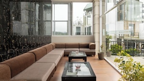 Una sala de estar moderna con un sofá modular, una mesa de centro de vidrio y grandes ventanas que ofrecen vista a la ciudad.