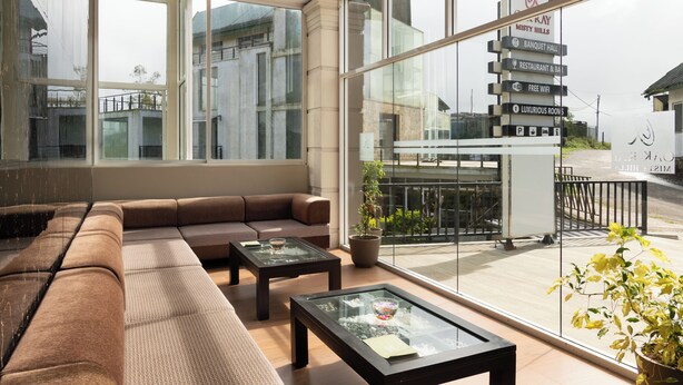 Un moderno vestíbulo de hotel con un amplio espacio para sentarse, una mesa de centro de vidrio y vistas al exterior.