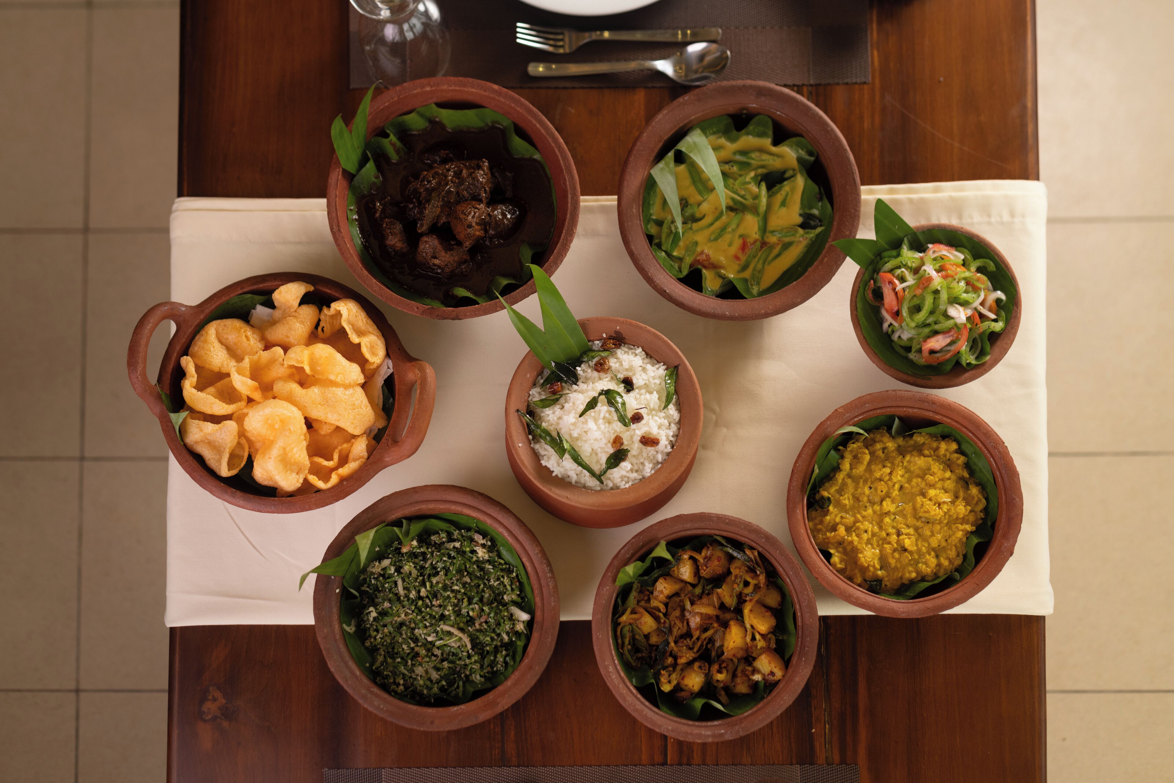 A table with various dishes in clay bowls, a plate, and cutlery.