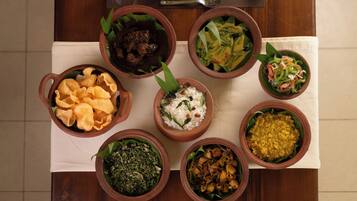 A table with various dishes in clay bowls, a plate, and cutlery.