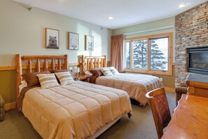 A hotel room with two beds, a stone fireplace, a large window with a view of trees, and a television. - Pool Access: North Shore Gem Near Beaches & Trails (Two Harbors)