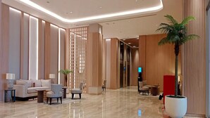 A spacious lobby with a polished marble floor, seating areas, and a large potted palm tree. - Apartemen Tokyo Riverside by Linkara (Teluknaga)