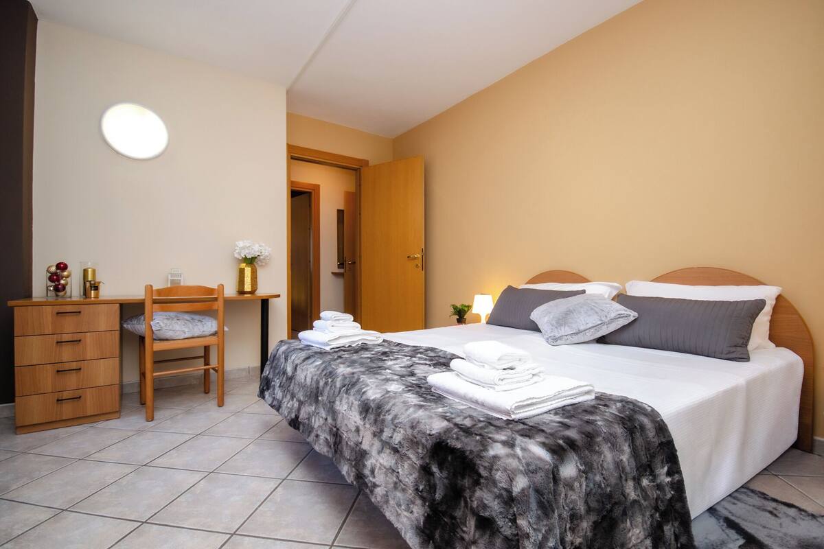 A neatly arranged bedroom with a bed, a desk, and a chair.