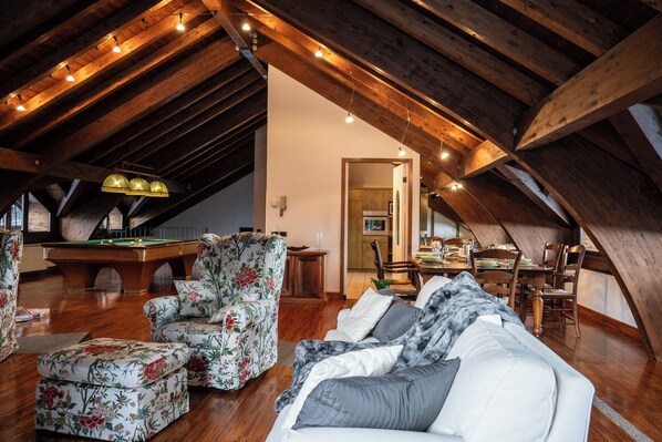 Un loft accogliente con tavolo da biliardo, poltrone floreali, un divano e zona pranzo.