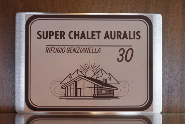 Schild für 'Super Chalet Auralis' mit Illustration von Berg und Sonne, das einen Gebirgsort kennzeichnet.