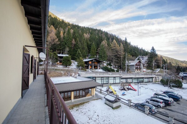 A ski resort with a parking area, a building with a ski lift, and a mountain backdrop.