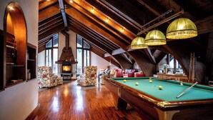 A spacious room with a pool table, wooden flooring, and a fireplace. - Rifugio Genzianella (Varzo)