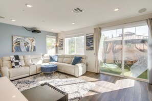 A modern living room with a sectional sofa, a coffee table, and a large sliding glass door leading to an outdoor area. - Home Theater System & Gazebo: Los Angeles Getaway! (San Fernando)