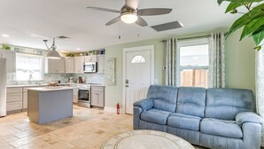 Eine moderne Küche mit einer zentralen Kochinsel, einem Essbereich mit blauem Sofa und einem Deckenventilator.