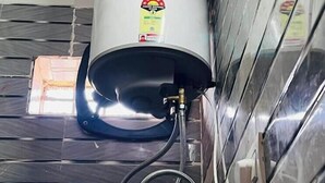 A water heater mounted on a tiled wall with a visible label. - Amrit Residency (Vrindavan)