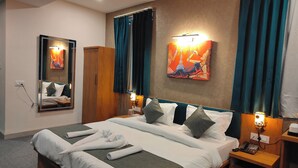 A hotel room with a large bed, a wardrobe, a bedside table with a lamp, and a painting on the wall. - Hotel The Muffet (Indore)
