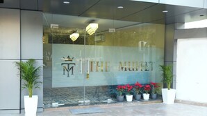 A hotel entrance with a glass facade, a logo, and potted plants. - Hotel The Muffet (Indore)