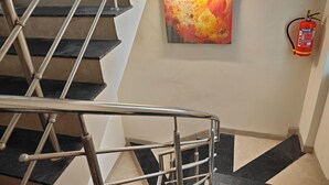 A staircase with a metal handrail and a fire extinguisher mounted on the wall. - Hotel The Muffet (Indore)