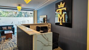 A reception area with a marble counter, a black chair, and a chandelier. - Hotel The Muffet (Indore)