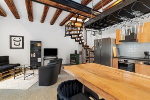 A modern kitchen with wooden beams, a staircase, and a dining area with a wooden table. - Apartment Historische Werkstatt – Romantic Stay in a Restored Monument (Gernsbach)