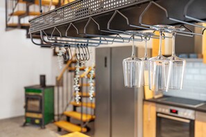 A kitchen with a hanging wine rack, a stove, and a dishwasher. - Apartment Historische Werkstatt – Romantic Stay in a Restored Monument (Gernsbach)