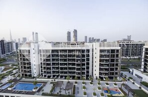 Un immeuble résidentiel moderne à plusieurs étages, doté d’une piscine sur le toit et d’espaces paysagers.