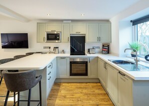 A modern kitchen with a central island, built-in appliances, and a large window.
