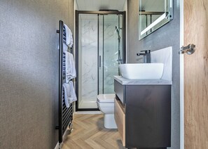 A modern bathroom with a glass shower enclosure, a white sink, and a toilet. - Kestrel Retreat S-Pod 4 (Millom)