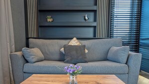 Un sofá gris con un jarrón de flores moradas sobre una mesa de centro de madera.