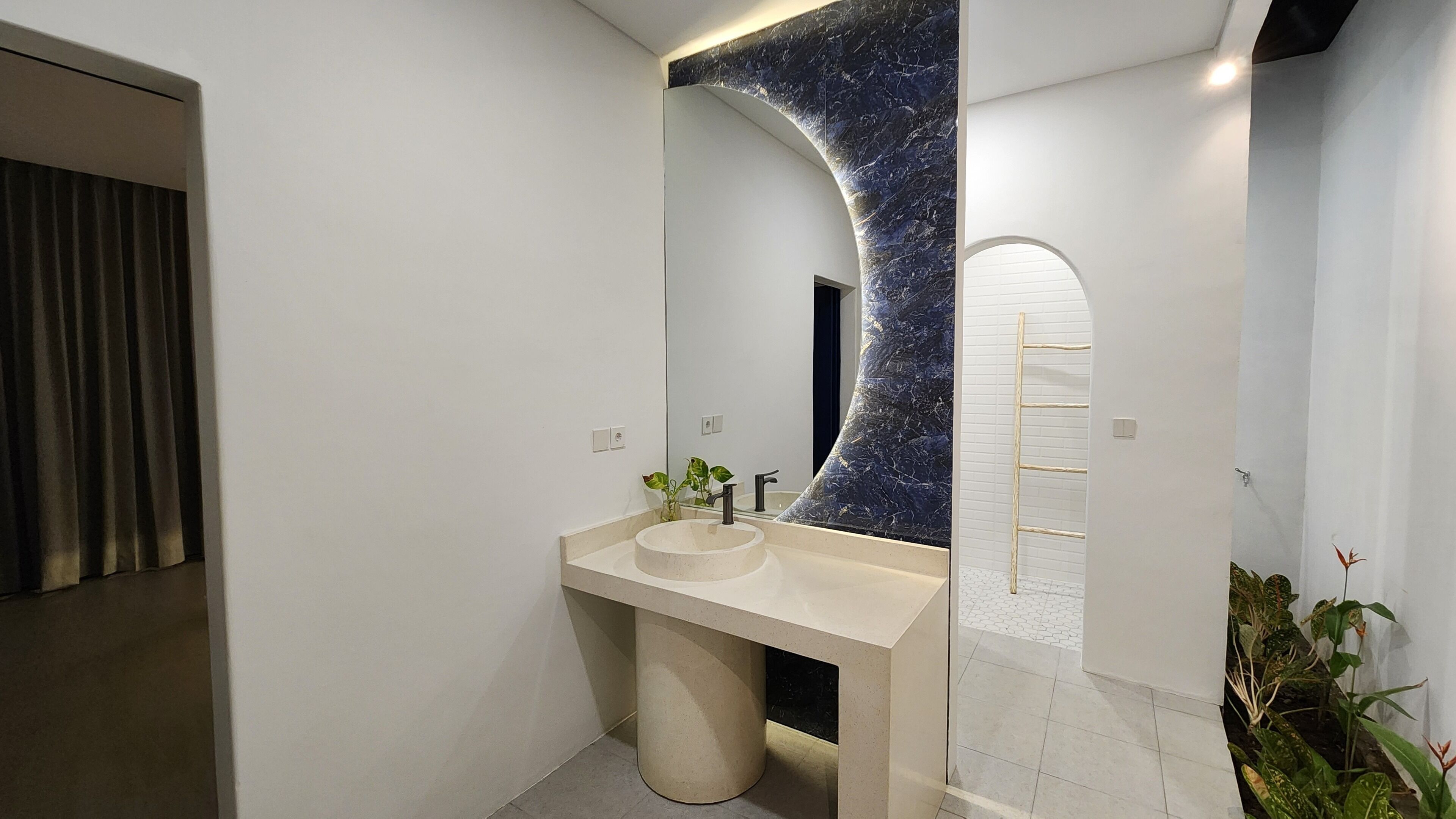 Un baño moderno con un espejo grande, un lavabo redondo y un salpicadero de mármol.