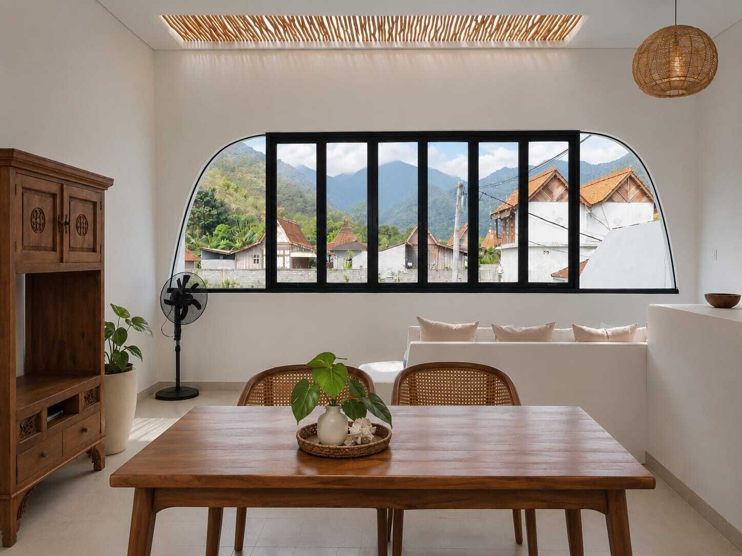 Comedor con mesa de madera, sillas y vista a casas a través de un ventanal grande.