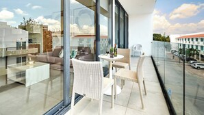 A modern balcony with wicker furniture, a glass table, and a view of the cityscape. - 2BR condo w/ pools, gym & balcony, steps to beach (Playa del Carmen)