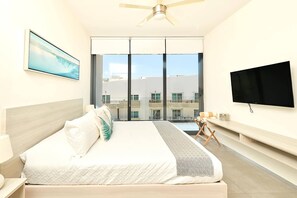 Une chambre d’hôtel avec un lit, une télévision, une fenêtre et un ventilateur de plafond.