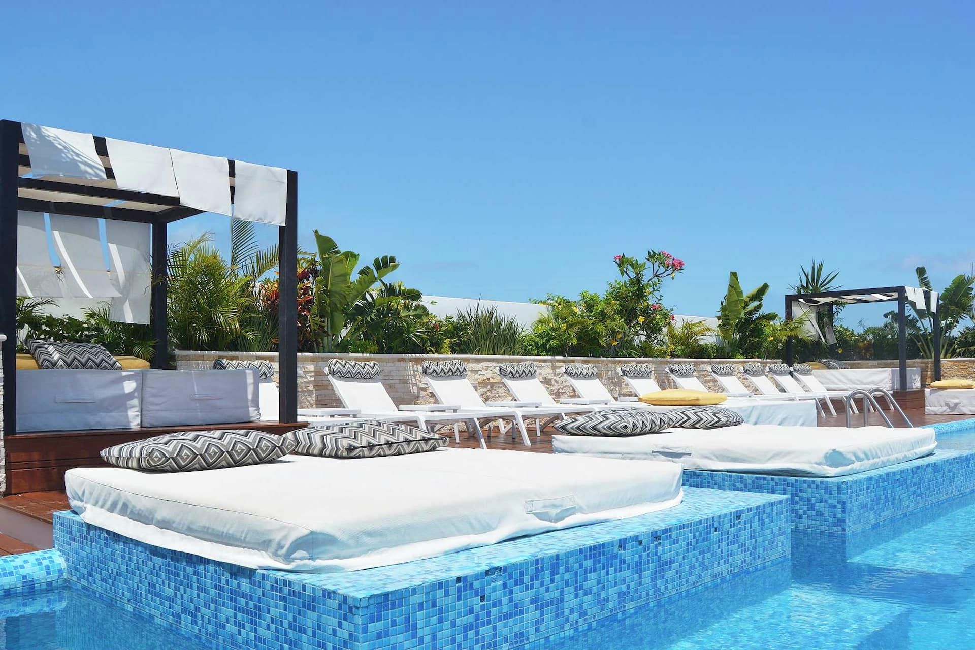 A rooftop pool area with lounge chairs and a covered seating area.