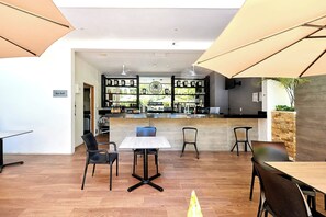 Ein Restaurant mit Barbereich, Holzboden und schwarzen Stühlen.