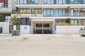 A modern building with a gated entrance, a parking area, and a sign indicating a sale. - 2BR condo w/ pools, gym & balcony, steps to beach (Playa del Carmen)