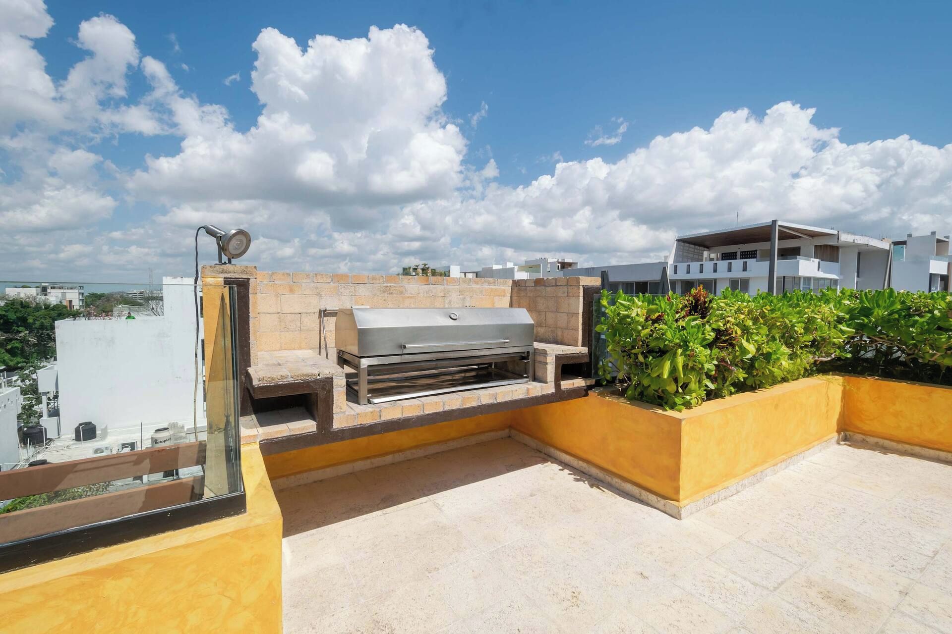 Eine Dachterrasse mit Grill, einer Sitzecke und Blick auf die Stadtlandschaft.