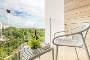 A balcony with a white chair, a potted plant, a wine glass, and a book. - Rooftop pool studio | steps to Coco Beach (Playa del Carmen)