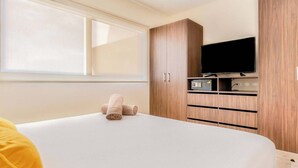 Una habitación de hotel con una cama, un televisor y armarios de madera.