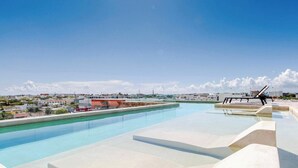 Una piscina en la azotea con vistas despejadas de los edificios circundantes y una costa lejana.