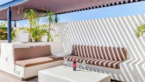 Un área de estar al aire libre con un sofá, una mesa, una botella de vino y plantas en macetas.