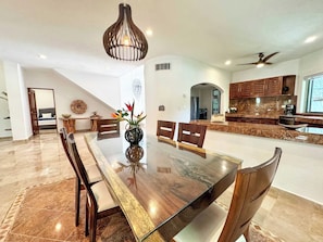 A modern kitchen with granite countertops, wooden cabinets, and a dining area with a glass table and wooden chairs. - Tropical 3BR retreat w/ pool & beach essentials (Playa del Carmen)
