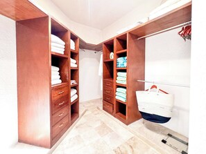A walk-in closet with wooden shelving, multiple drawers, and hanging space.
