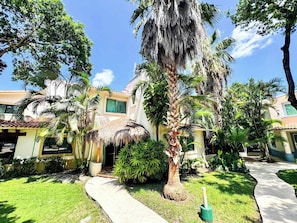 A resort with palm trees, a thatched-roof structure, and a paved walkway. - Tropical 3BR retreat w/ pool & beach essentials (Playa del Carmen)