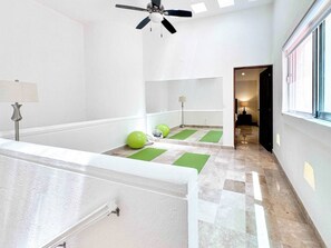Ein Hotelzimmer mit Deckenventilator, Fenster, Lampe und Übungsbällen auf einer grünen Matte.