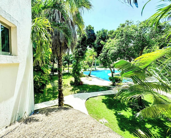 A pool area with a clear blue pool, surrounded by lush greenery and palm trees. - Tropical 3BR retreat w/ pool & beach essentials (Playa del Carmen)
